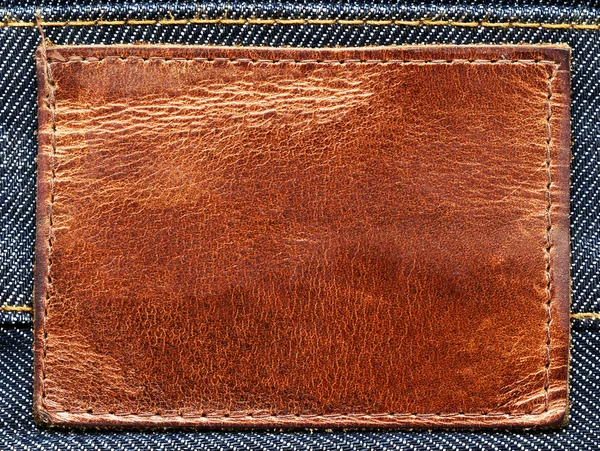 Tom grungy brunt läder etikett på vintage blå denim — Stockfoto