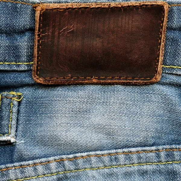 Etichetta in pelle grigia bianca su denim vintage azzurro — Foto Stock