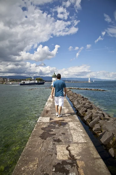 Młody człowiek chodzenie w Jet d'Eau doku w Genewie — Zdjęcie stockowe