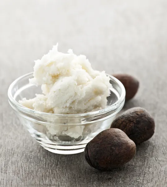 Shea butter and nuts in bowl — Stock Photo, Image