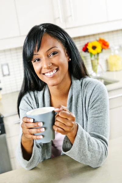 Mutfakta elinde kahve bardağıyla bir kadın. — Stok fotoğraf