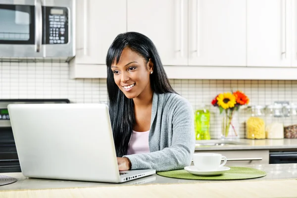 Жінка використовує комп'ютер на кухні — стокове фото