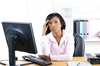 Worried black businesswoman at desk clipart