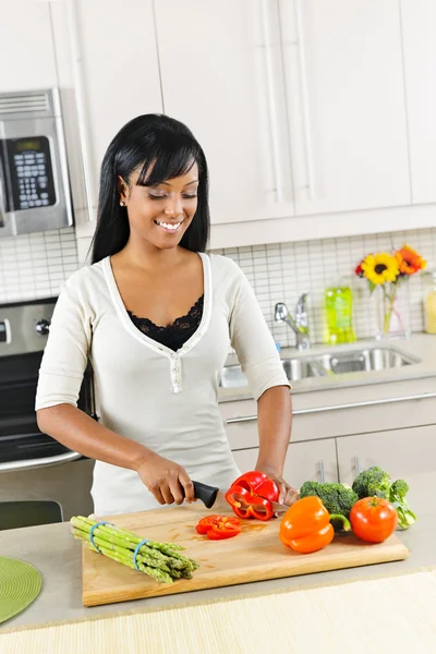 Mulher jovem cortando legumes na cozinha — Fotografia de Stock