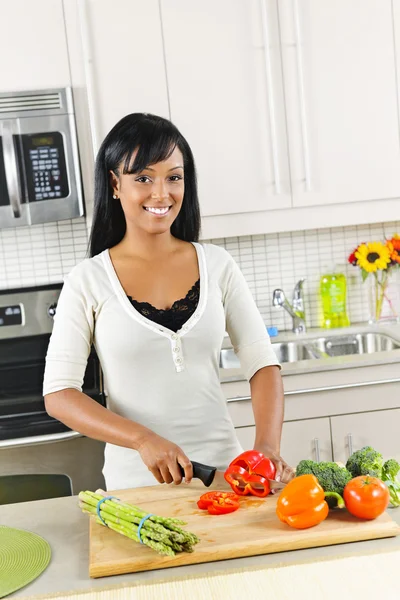 Jeune femme coupant des légumes dans la cuisine — Photo