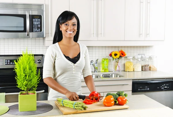 Giovane donna che taglia verdure in cucina — Foto Stock