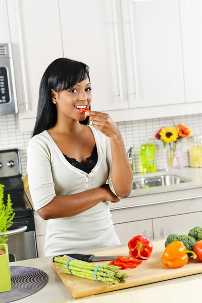 Mladá žena, ochutnávka zeleniny v kuchyni — Stock fotografie
