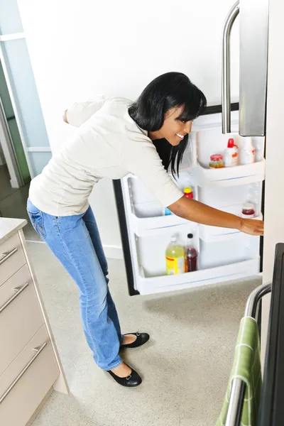 Junge Frau schaut in Kühlschrank — Stockfoto