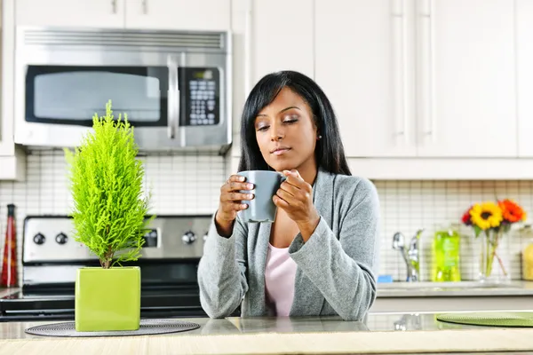 Mutfakta elinde kahve bardağıyla bir kadın. — Stok fotoğraf