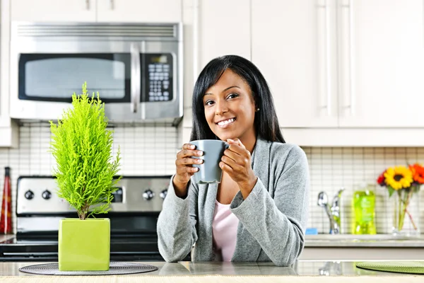 Vrouw in keuken met koffiebeker — Stockfoto