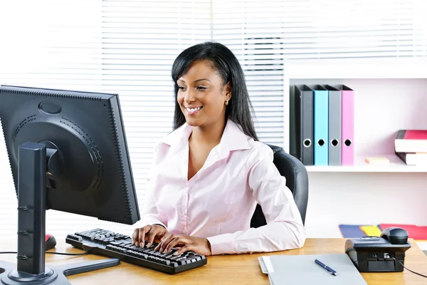 Sonriente mujer de negocios negra en el escritorio —  Fotos de Stock