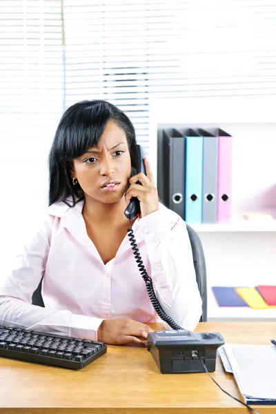 Berörda svart affärskvinna på telefon på skrivbordet — Stockfoto