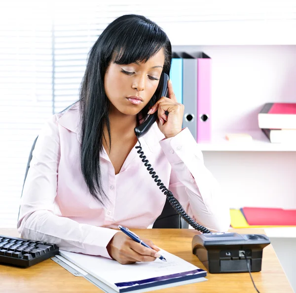 Allvarliga svart affärskvinna på telefon på skrivbordet — Stockfoto