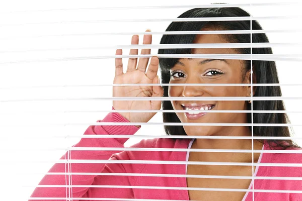 Lachende vrouw op zoek via blinds — Stockfoto