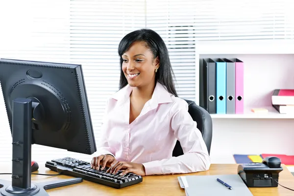 Sonriente mujer de negocios negra en el escritorio Imagen de archivo