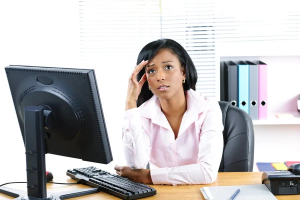 Besorgte schwarze Geschäftsfrau am Schreibtisch Stockbild