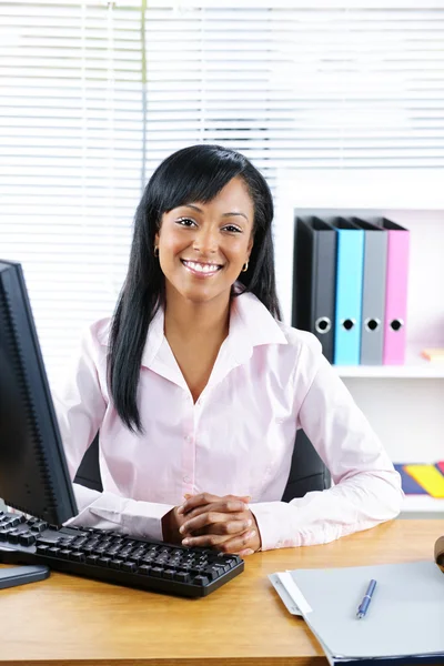 Leende svart affärskvinna på skrivbord Stockbild