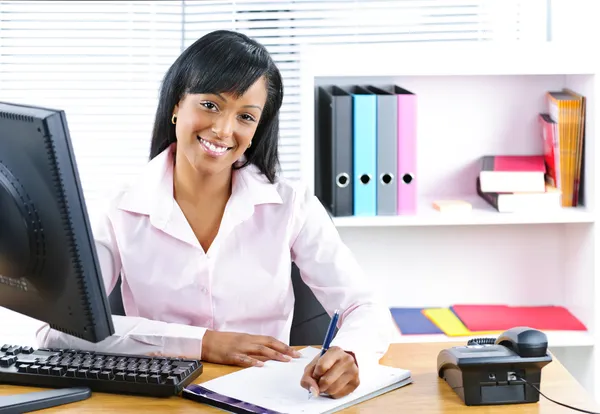 Sonriente mujer de negocios negra en el escritorio Imagen de archivo