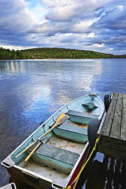 Rowboat docked on lake clipart