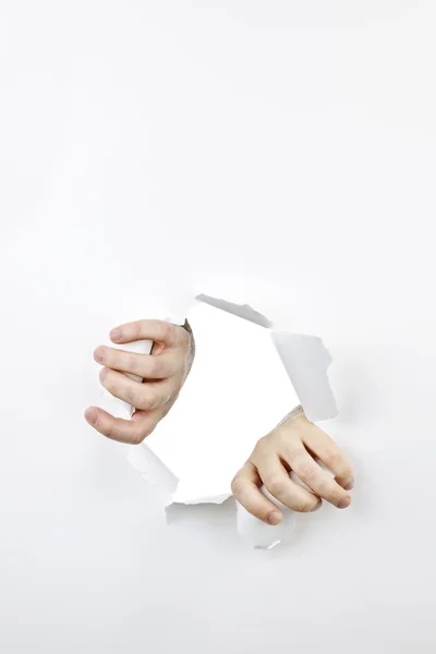 Mãos rasgando através do furo no papel — Fotografia de Stock