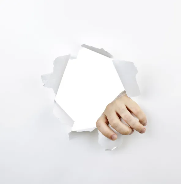 Hand ripping through hole in paper — Stock Photo, Image
