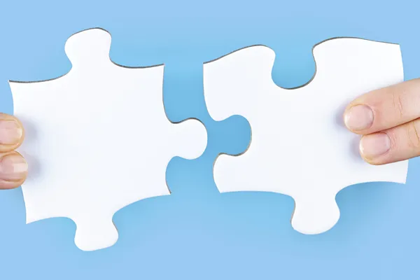 Fingers holding jigsaw puzzle pieces — Stock Photo, Image