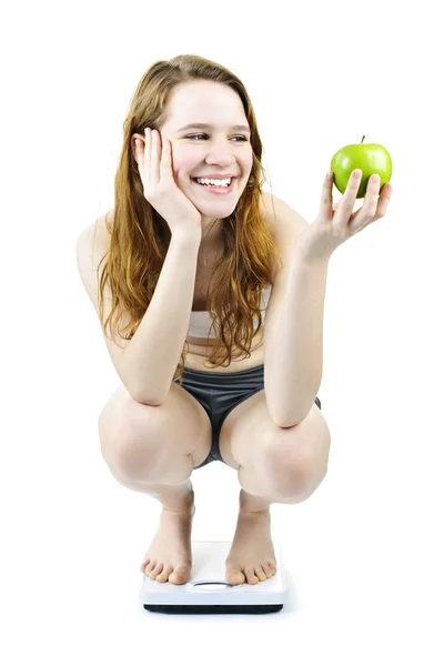 年轻的微笑女孩上秤持有苹果 — 图库照片
