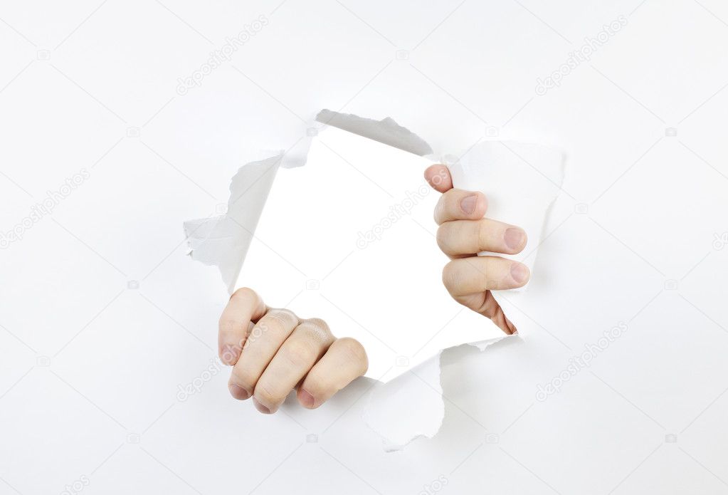 Hands ripping a hole in white paper with torn edges