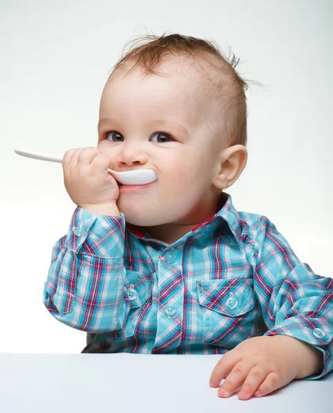 Cute little boy is biting spoon — Stock Photo, Image