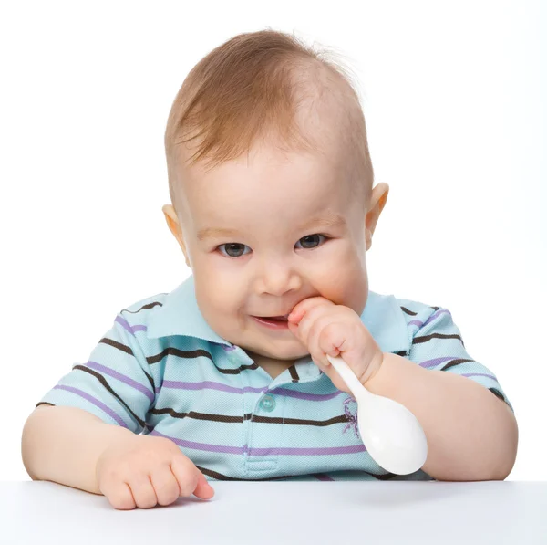 Милый маленький мальчик кусает ложку — стоковое фото