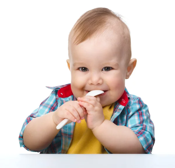 Милый маленький мальчик кусает ложку — стоковое фото