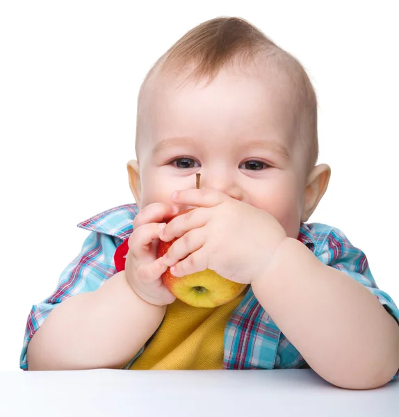 Criança está mordendo maçã vermelha e sorriso — Fotografia de Stock