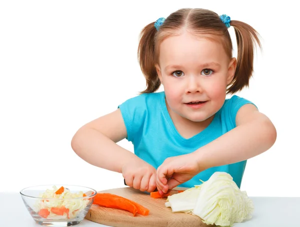 Маленькая девочка режет морковку для салата — стоковое фото