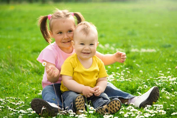 Deux enfants sont assis sur la prairie verte — Photo