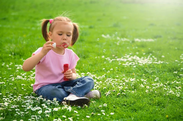 A menina está sentada no prado verde — Fotografia de Stock