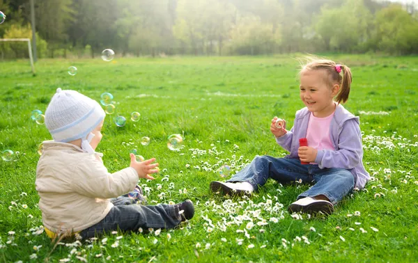 Двоє дітей сидять на зеленому лузі — стокове фото