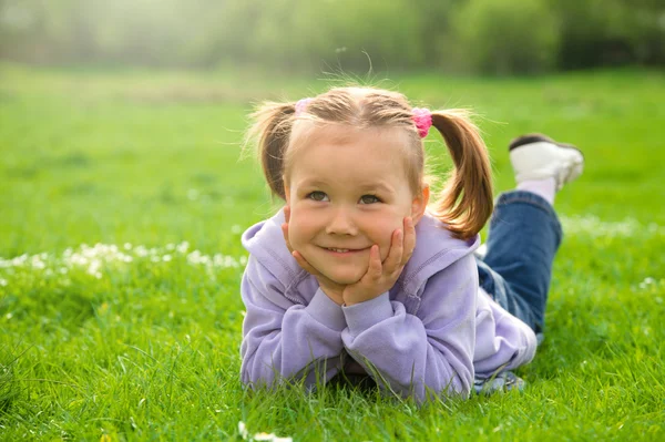 어린 소녀 녹색 풀밭에 누워 있다 — 스톡 사진