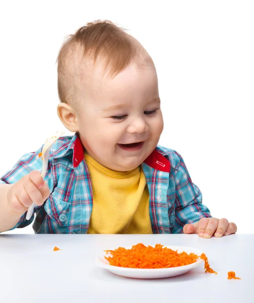 Menino bonito está brincando com salada de cenoura — Fotografia de Stock