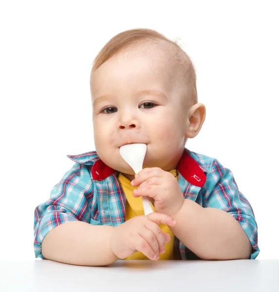 Милий маленький хлопчик кусає ложку — стокове фото