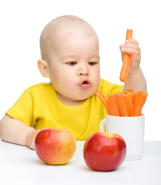 Little boy pulling up carrot from a cup — Stock Photo, Image