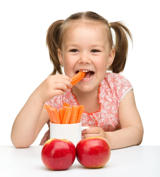 Милая маленькая девочка ест морковь и яблоки — стоковое фото