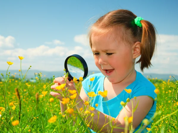 Klein meisje onderzoeken bloemen met Vergrootglas — Stockfoto