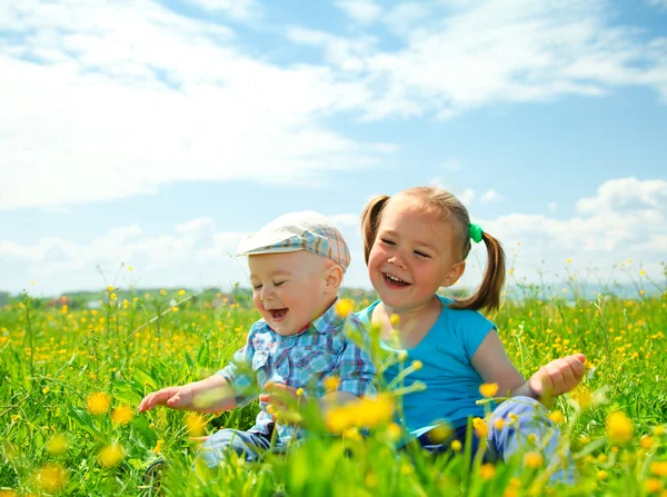 Deux enfants s'amusent sur la prairie verte — Photo