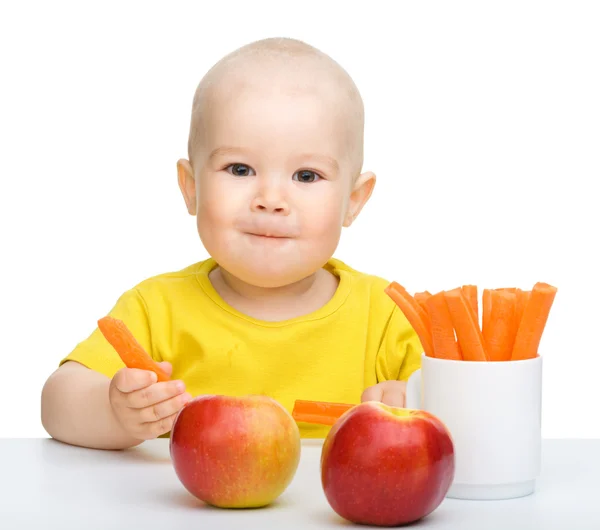 Bonito menino come cenoura e maçãs — Fotografia de Stock