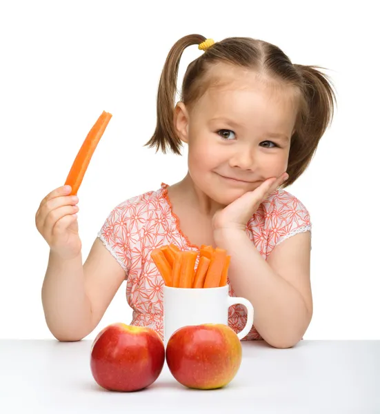 Sevimli küçük kız havuç ve elma yiyor. — Stok fotoğraf