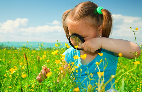 Bambina esaminando fiori utilizzando lente di ingrandimento — Foto Stock