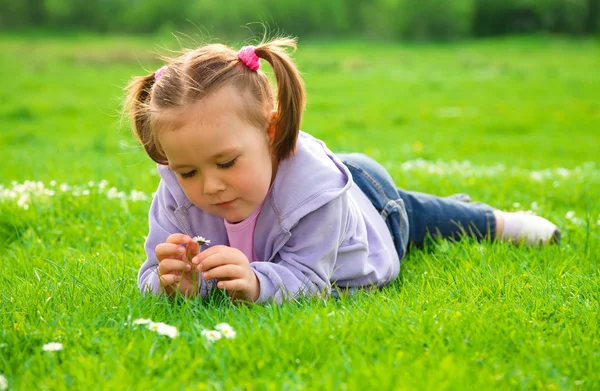 Kleines Mädchen liegt auf grüner Wiese — Stockfoto
