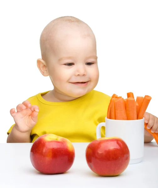 Milý chlapeček jí mrkev a jablka — Stock fotografie