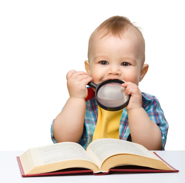 Liten barn lek med bok och förstoringsglas — Stockfoto