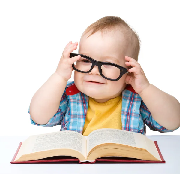 Маленький ребенок играет с книгой и очками — стоковое фото